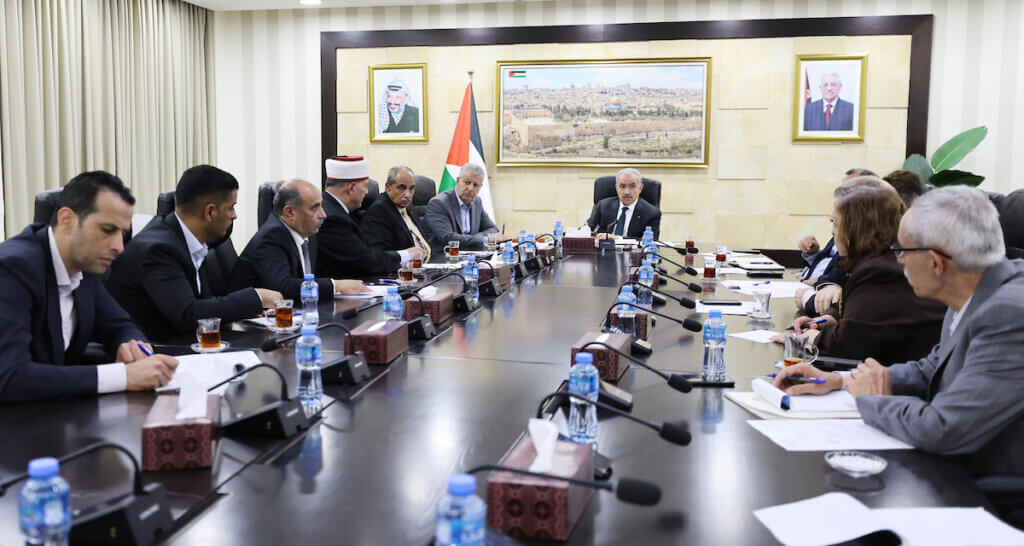 Palestinian Prime Minister Mohammed Shtayyeh sits at the head of a table and chairs a meeting of the ministerial committee on the reconstruction of Jenin refugee camp, in the West Bank city of Ramallah on July 6, 2023.